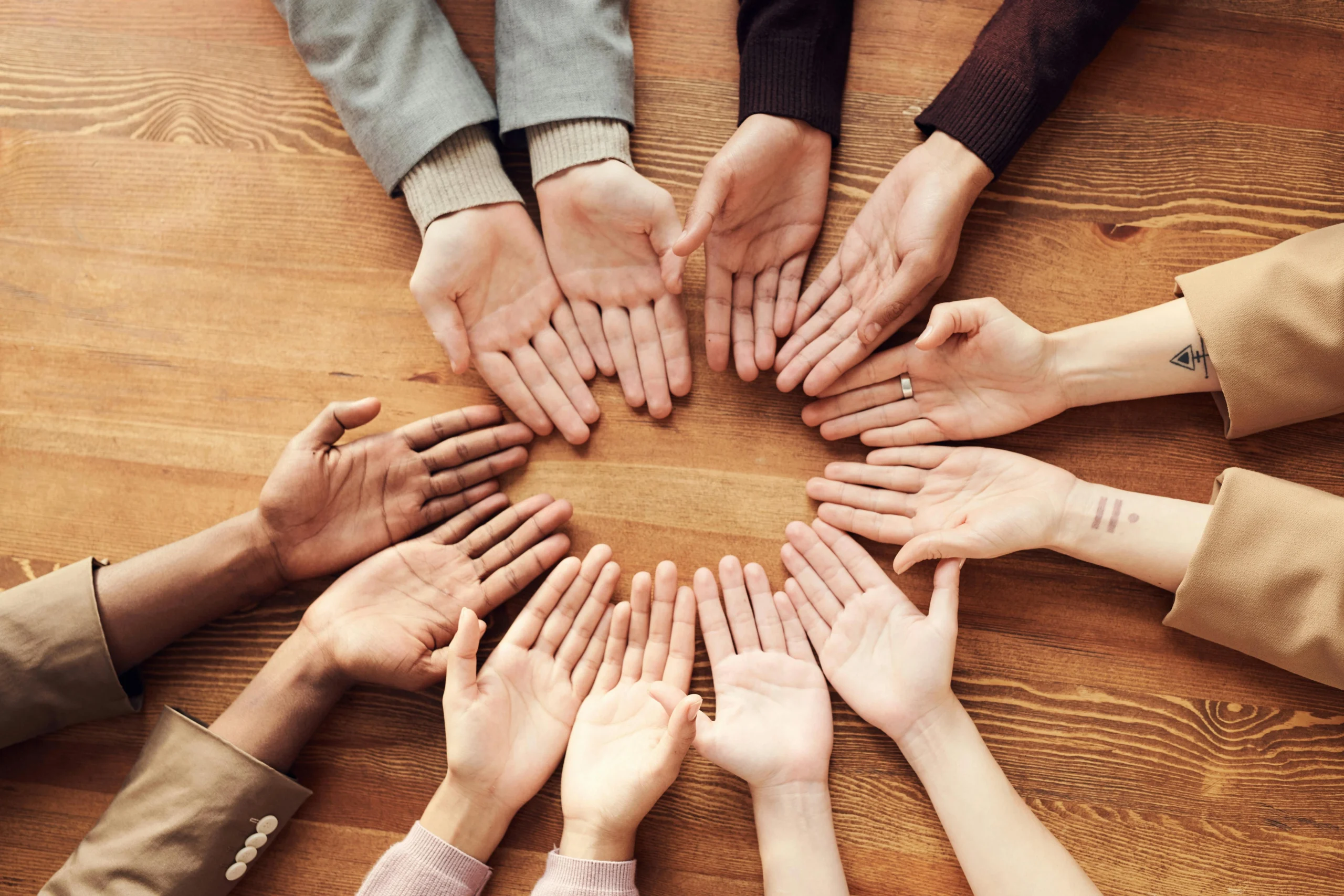 Mani in cerchio con i palmi rivolti verso l’alto, simbolo di inclusione e collaborazione per la politica per la diversità autistica.